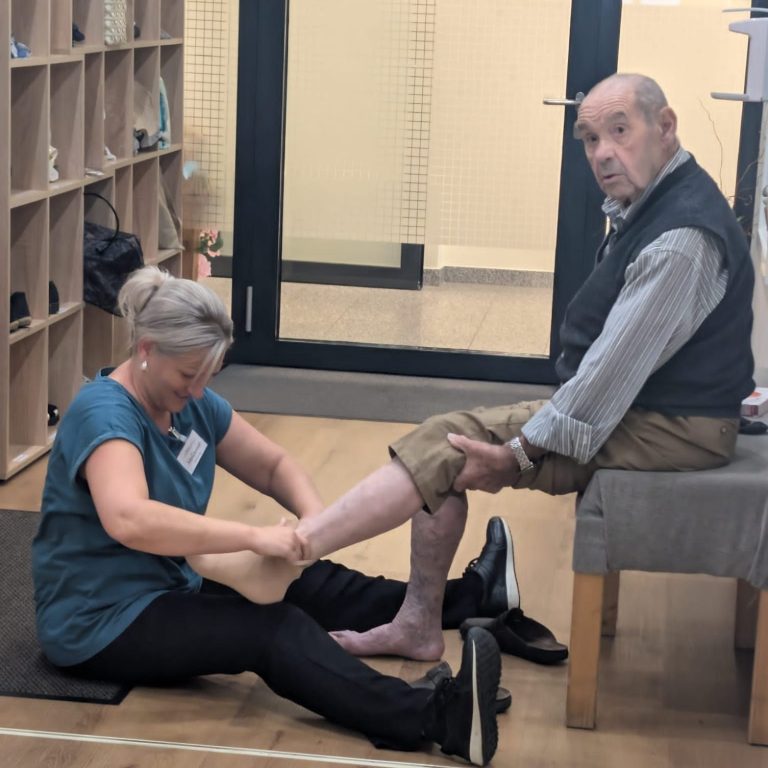 Pflegekraft hilft einem Bewohner mit Rollator beim Gehen